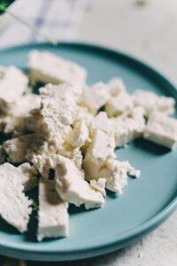 Delicious crumbled feta cheese on a blue plate, perfect for salads and Mediterranean dishes.